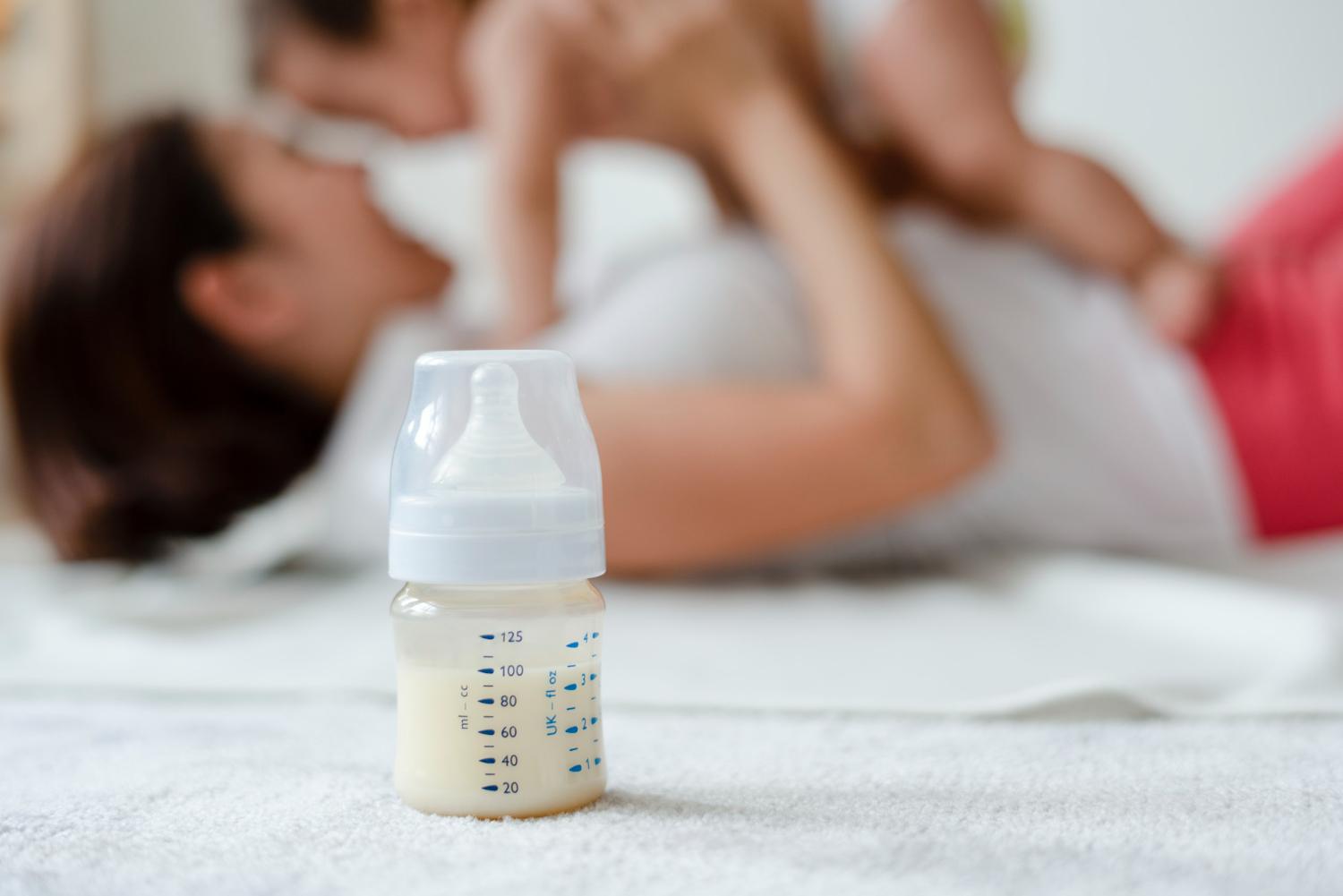 Parent preparing a formula bottle on a kitchen counter