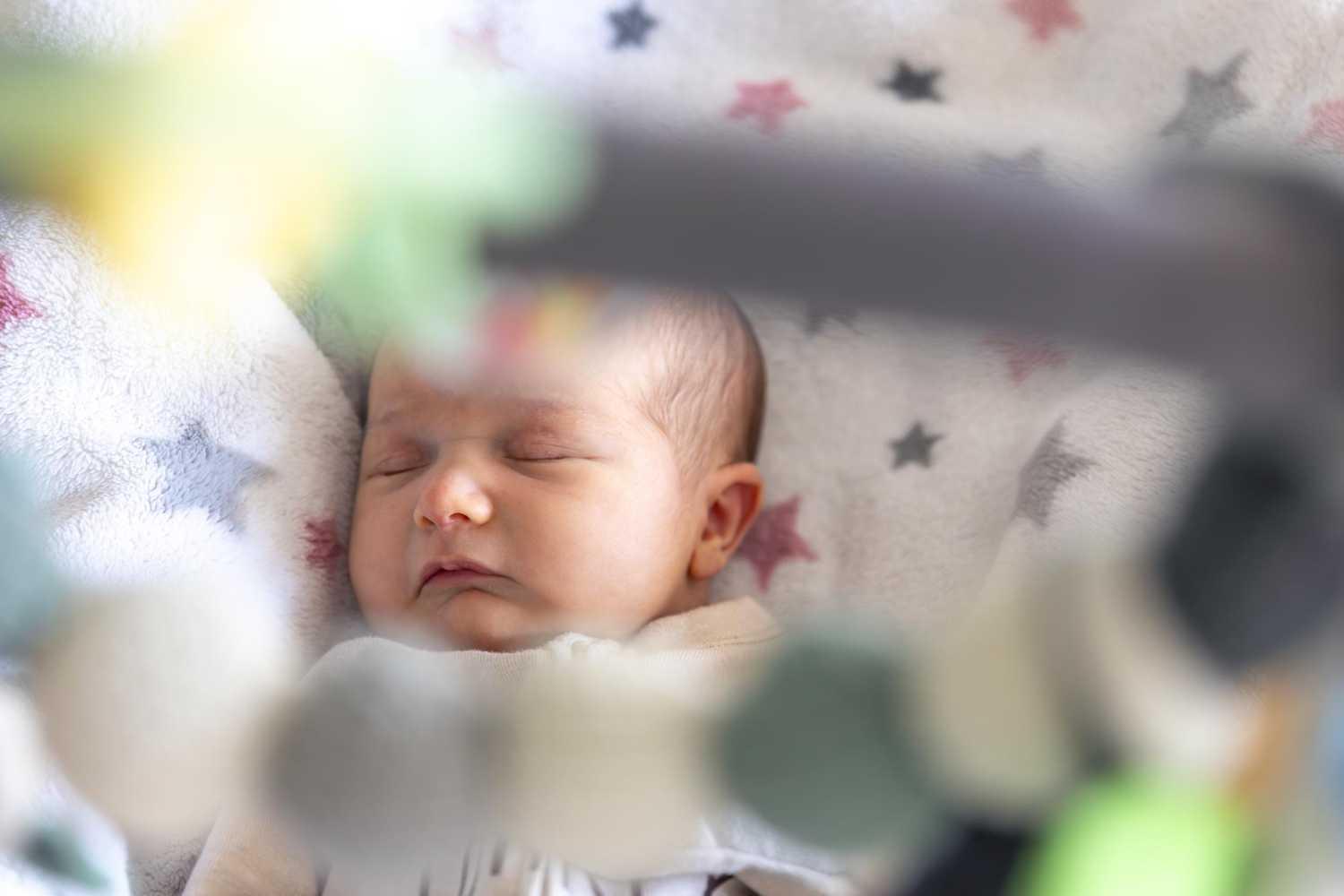 Sleeping newborn swaddled in soft bassinet light