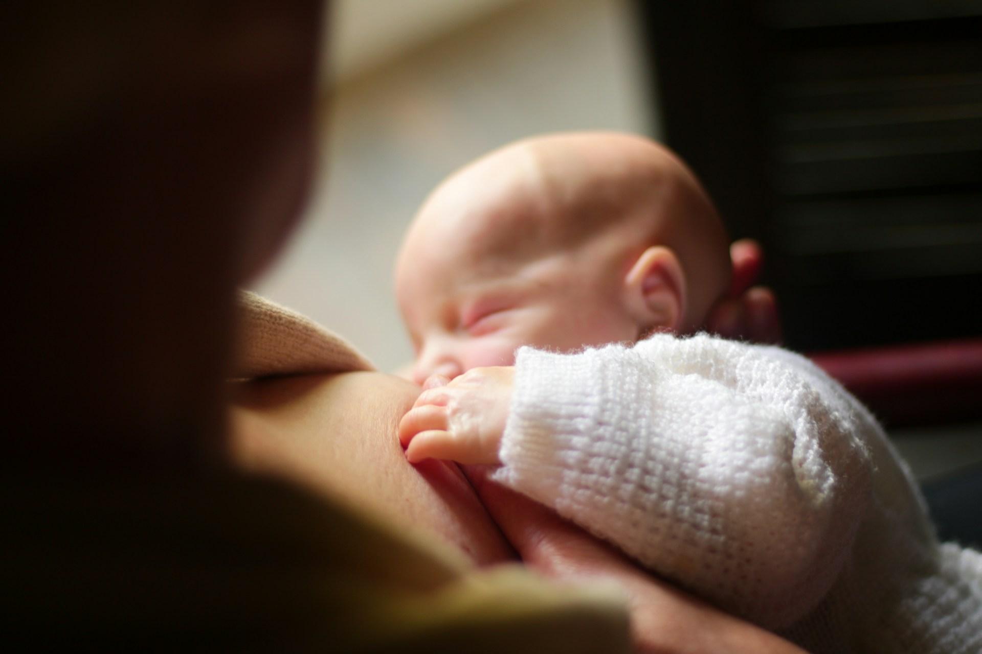 Close-up of mother breastfeeding newborn with gentle hand support