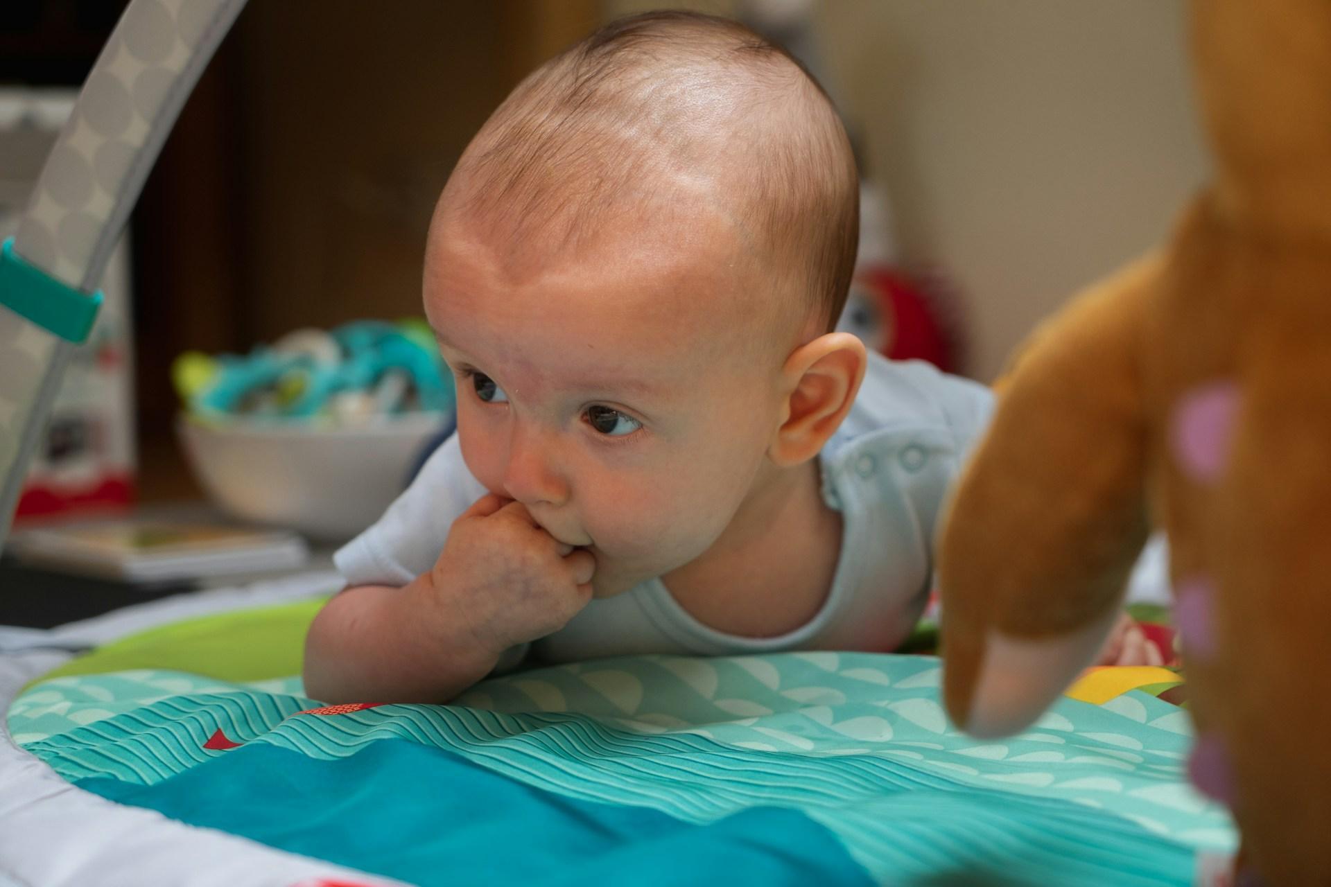 Parent smiling at one-month-old baby during tummy time