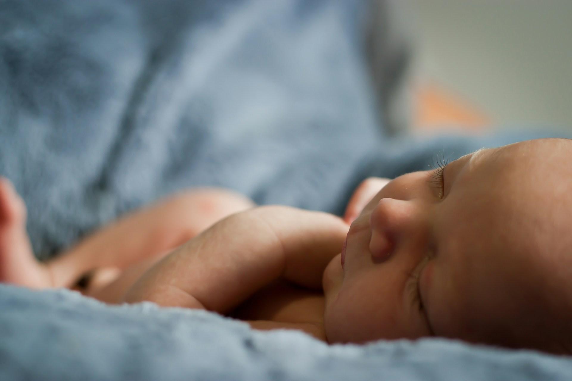 Mother breastfeeding with supportive hand on tender breast