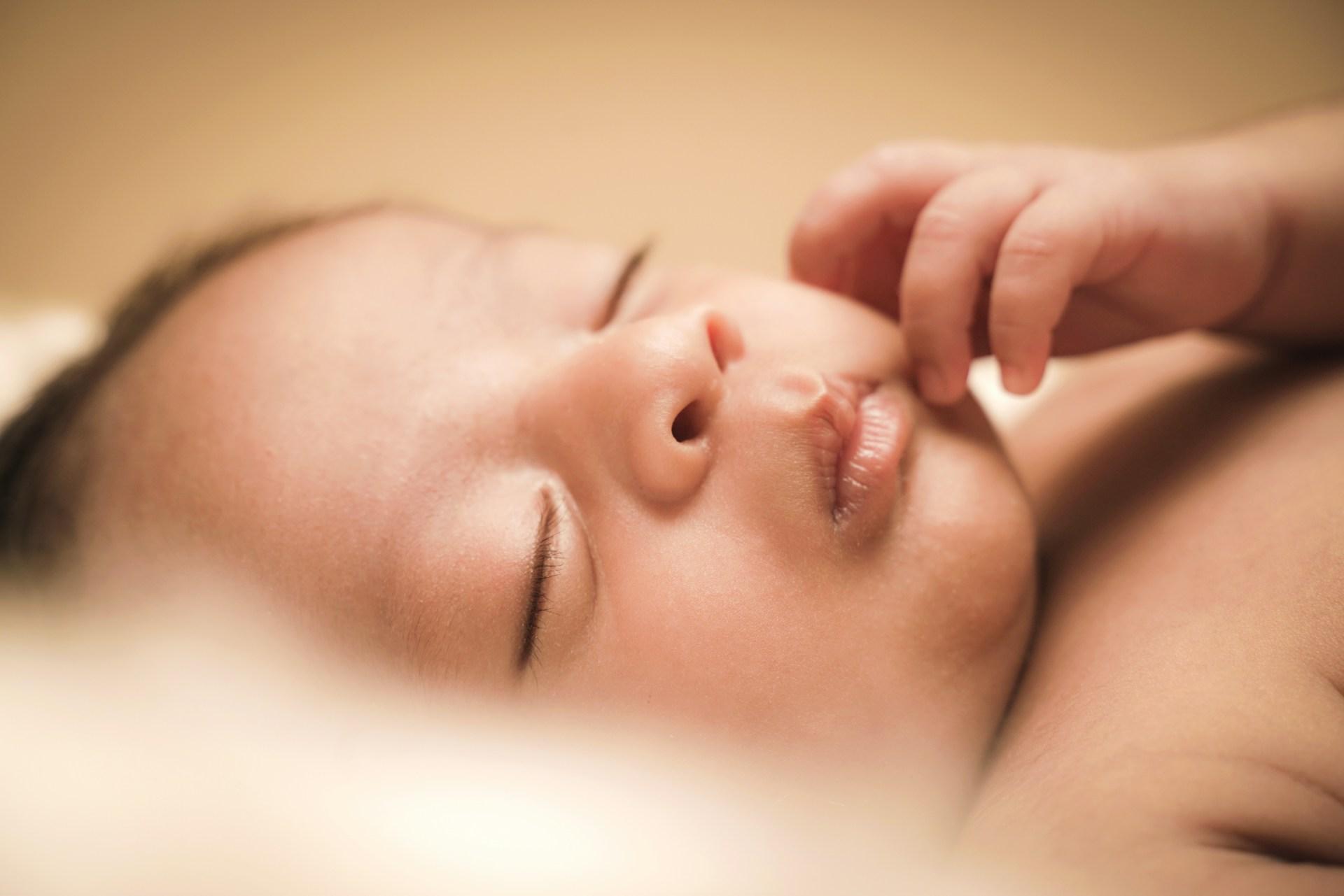 Forælder holder nyfødt baby tæt under amning
