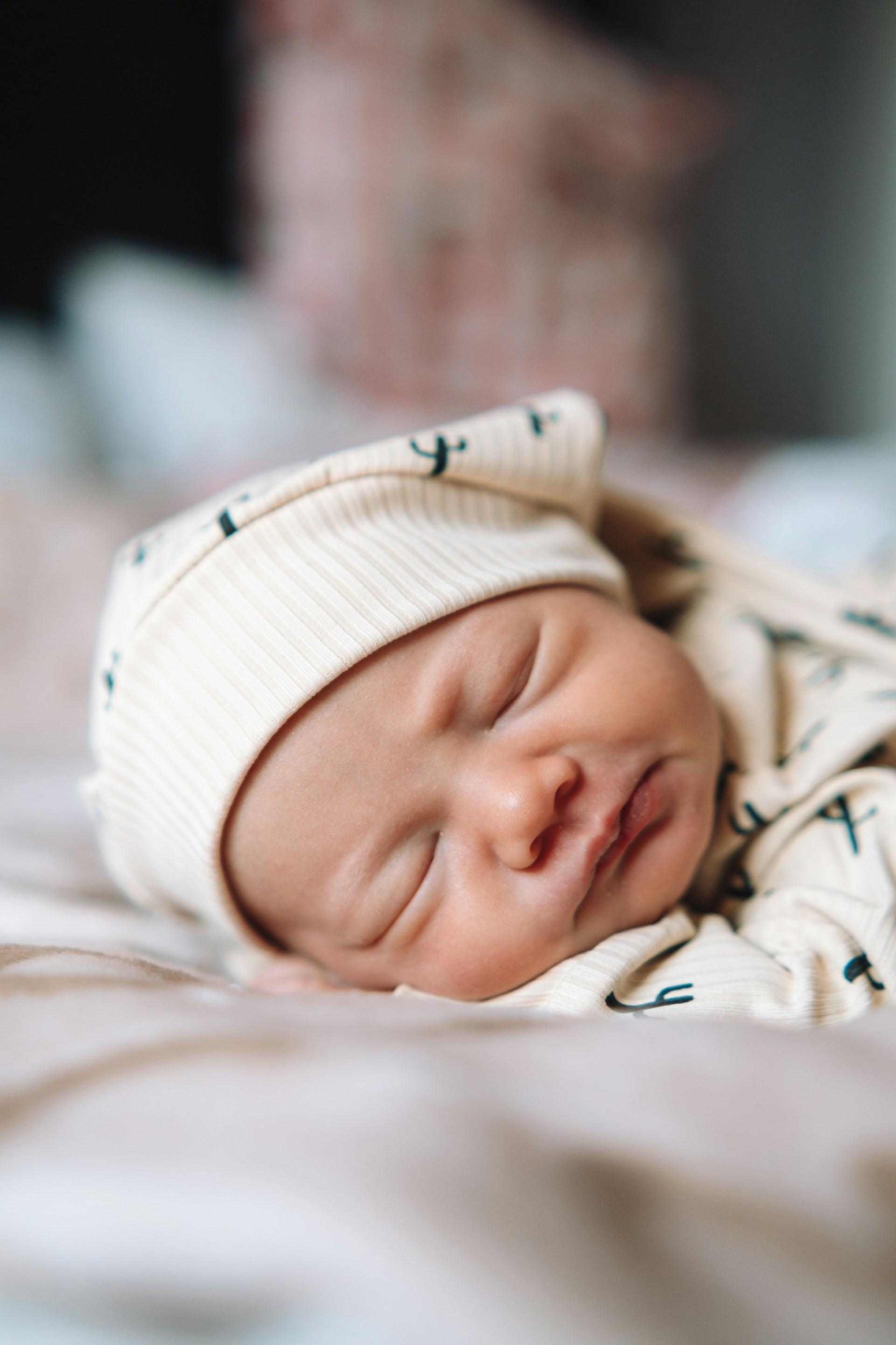 Sleeping newborn in swaddle by dim bedside